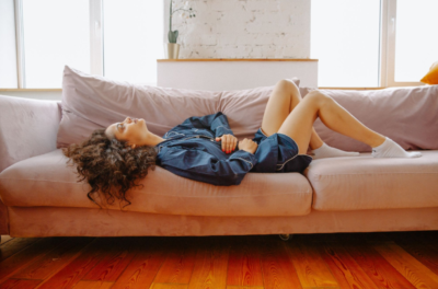 woman lying on a sofa clutching her stomach