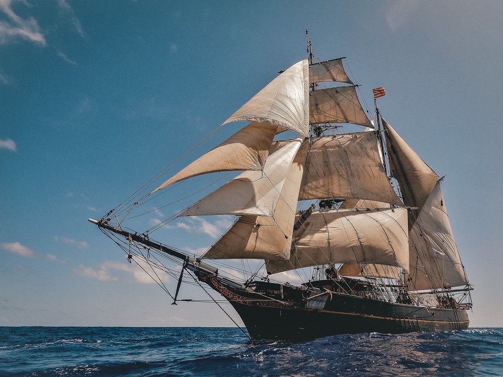 A photo of a giant ship with three sails at sea