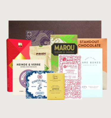 Picture of our deluxe vegan box on a grey background. The bars are positioned in front of a brown box with a cocoa runners label on the front in gold.