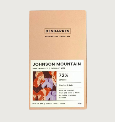 Desbarres 72% johnson mountain bar on a grey background. The packaging is a very light orange colour, with a white label that has a small square of an lilac, burnt orange, orange and dark purple geometric pattern.