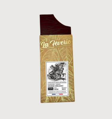 Hasnaa's Idukki india dark bar on a grey background. The bar is paper brown, with gold leaves all over it. The logo is in gold writing, and the label on the front of the bar is black and white, with a sketch of monkeys on it.