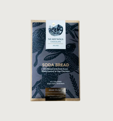 NearyNogs Irish Sodabread bar on a grey background. The packaging is elegant, and is grey with a darker grey cartoon outline of a hare on the front. The bar is outlined with a shiny gold rim, and has a white label at the top.