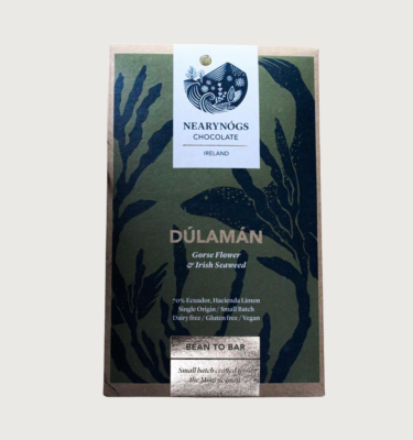 NearyNogs' gorse and seaweed bar on a grey background. The bar is a dark cool toned olive green, with cartoon navy seaweed all over it. The writing on the bar is gold, and there is a white label at the top.