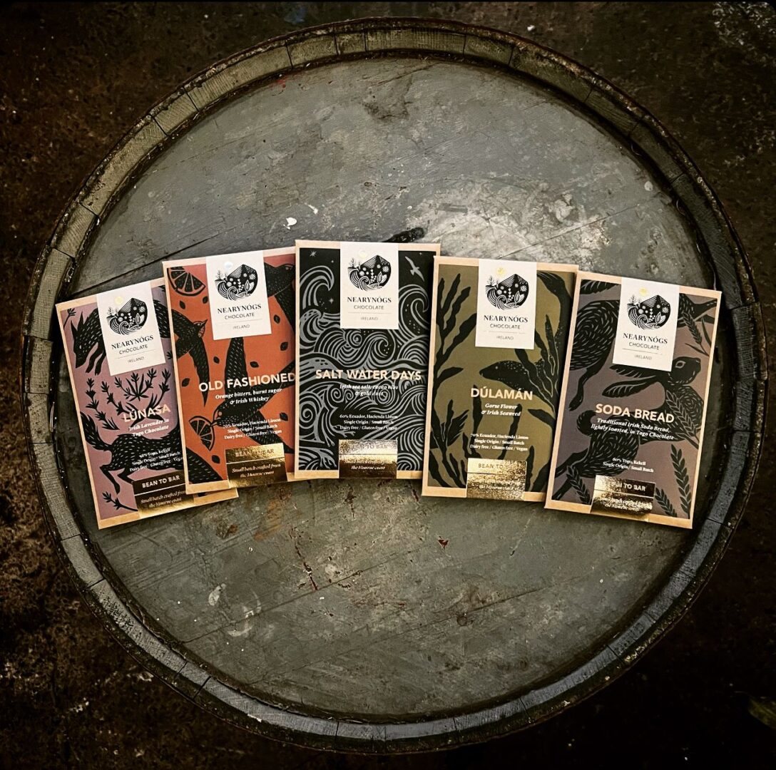 A shot of Nearynogs' irish collection of bars. There are 5 bars with different coloured packaging, spread out on top of a barrel. The photo is taken from a birds-eye view perspective