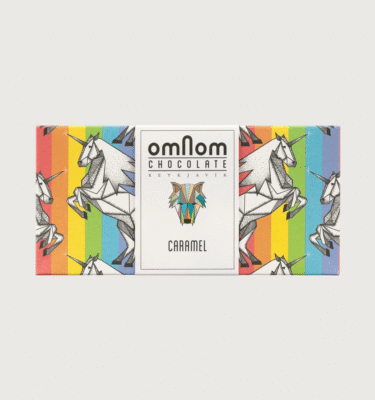 An omnom bar on a grey background. The packaging is rainbow with unicorns on it to celebrate pride