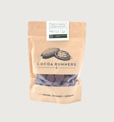 Original beans' 42% milk couverture in a 230g bag on a grey background. The bag is a light tanned brown, with a black sketch of cocoa pods just above the cocoa runners logo. There is a gap in the packaging which has been replaced with clear plastic, so you can see the buttons.