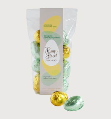 Picture of pump street's dark eggs on a grey background. The eggs are wrapped in yellow and pale green foil.