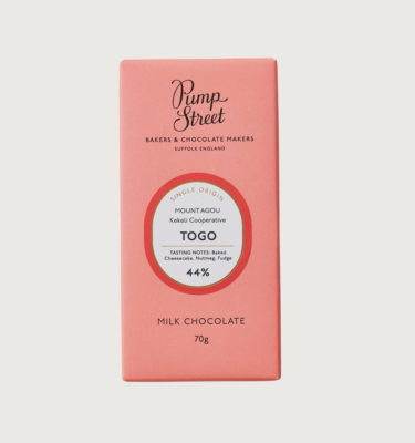 A baby pink bar, with black writing. In the centre, there is an oval white label with black writing, surrounded by a bright red border.