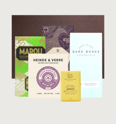 Picture of our vegan box on a grey background. There are five bars organised in front of a dark brown cocoa runners box.