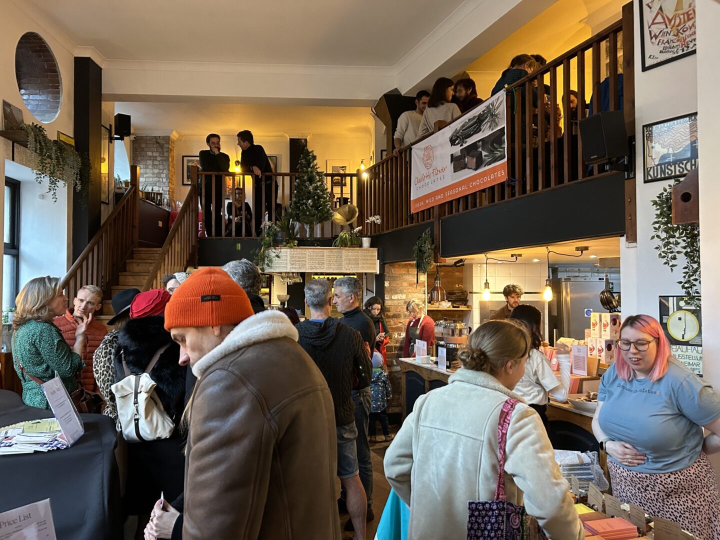 A busy room with two floors, with lots of chocolate makers and people speaking to them at stalls
